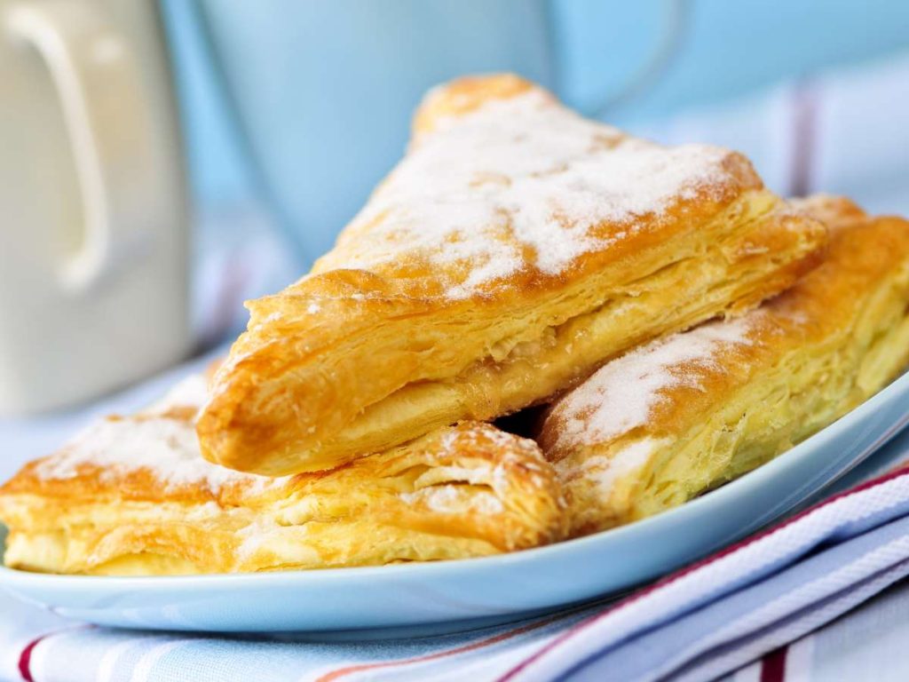 A plate of apple turnovers covered in powdered sugar.