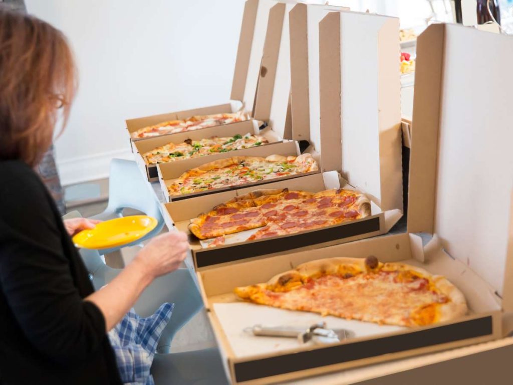 A woman selecting which pizza to eat at a pizza buffet.