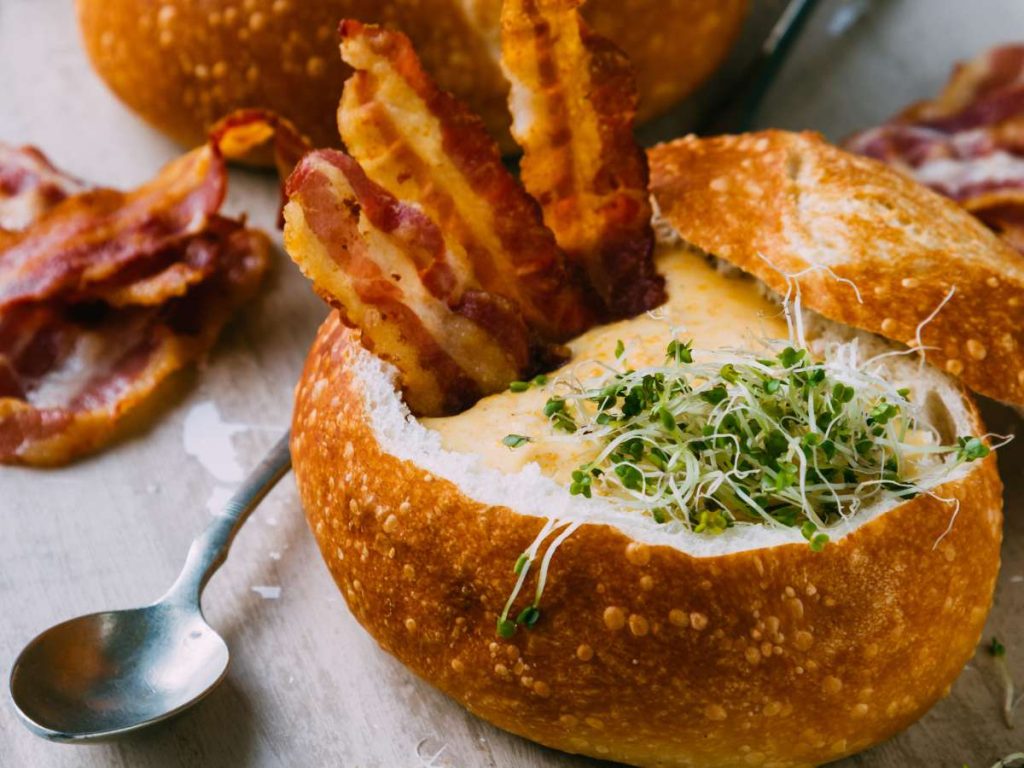 A bread bowl with bacon and seasonings inside.
