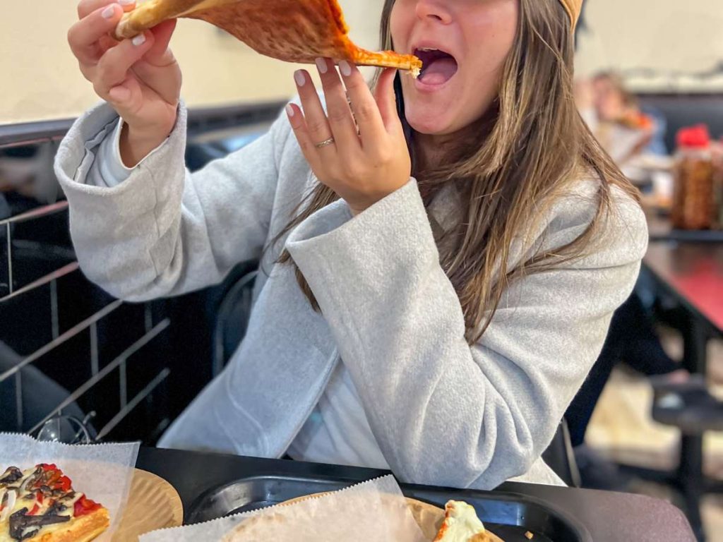A woman eating a slice of New Jersey pizza.