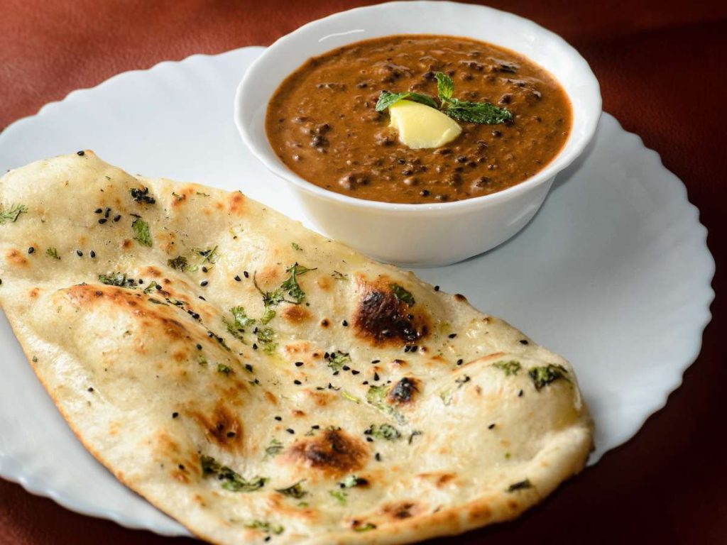 A naan bread on a plate with a bowl of dip.