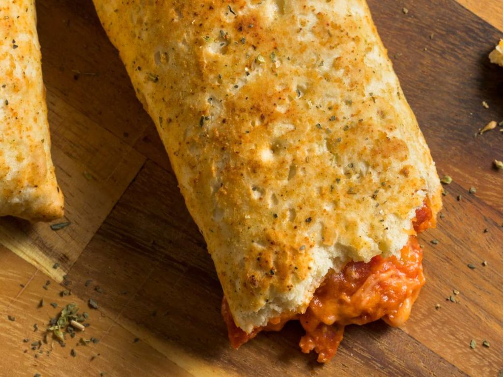 A pizza pocket with a bite taken out of it.