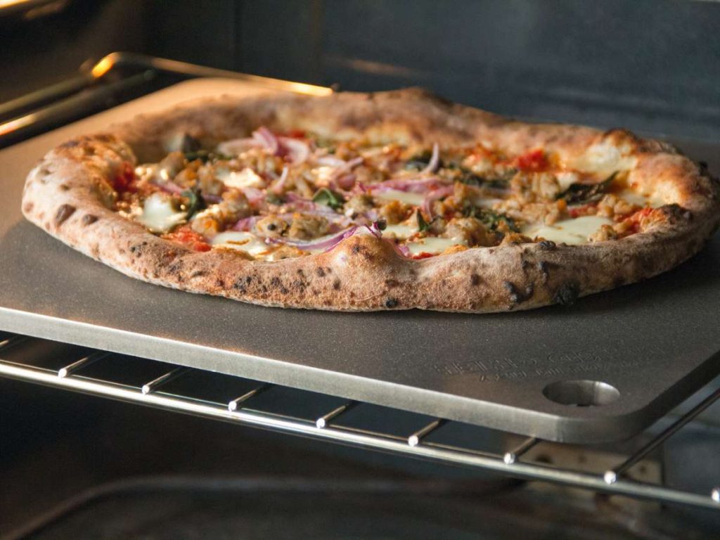 A pizza cooking on a pizza steel in a home oven.