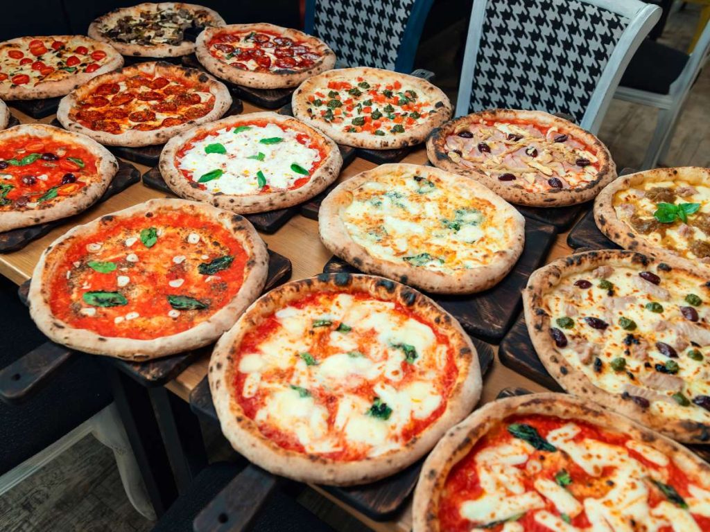Several Neapolitan style pizzas arranged on a table for serving.