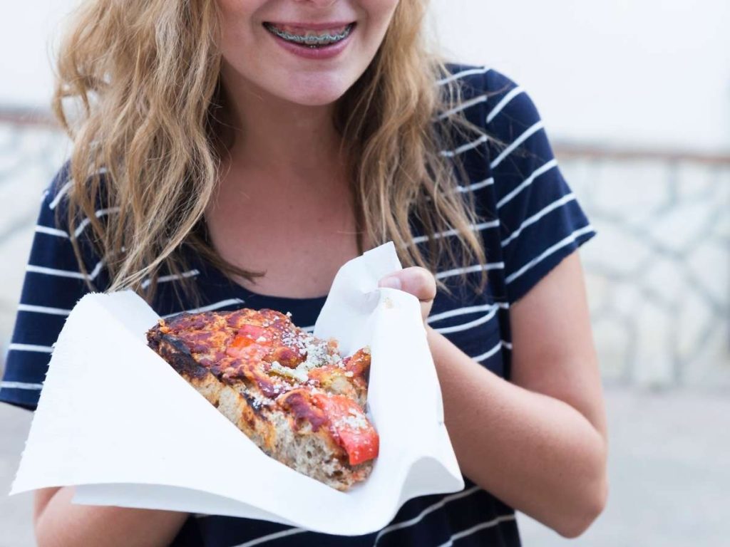 A young girl with braces about to eat a thick slice of pizza.
